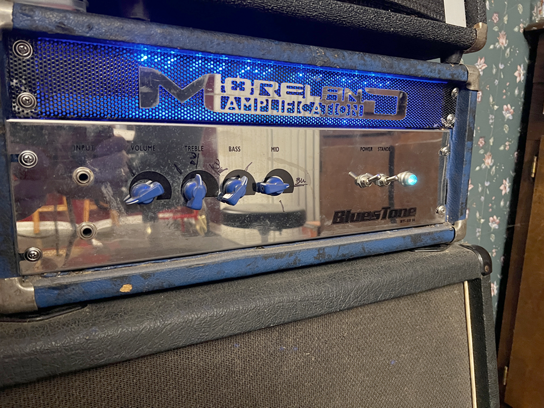 Badge backlit through perforated steel mesh — the identity functioning as a permanent product component